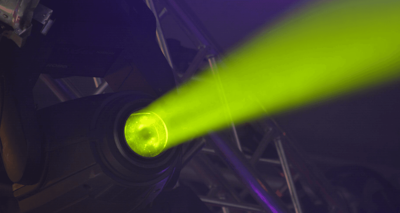 A bright lime-green spotlight beam cutting through a dark room, mounted on a metal stage truss. The concentrated light serves as a visual metaphor for cognitive attention and the ability of a focused mind to isolate specific information.